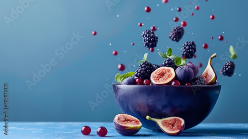 A cascade of blackcurrant and fig slices dropping into rich purple acai bowl, against an indigo background, copy space