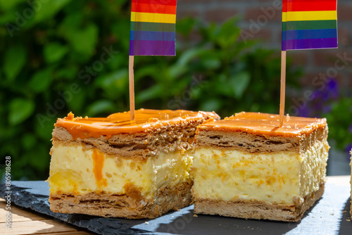 Celebration of the King birthday in Netherlands, tompoes or tompouce, iconic pastry in Netherlands made from puff dough, orange icing, cream and rainbow lgbt pride flag