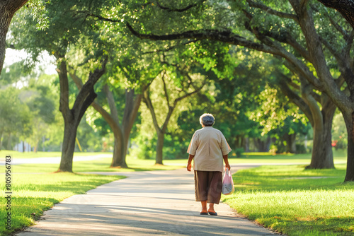 An elderly Hispanic woman taking a morning stroll through a tranquil suburban park, embracing the peace and quiet of the natural surroundings.