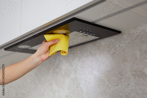 Woman hand cleaning range hood in the kitchen with a rag or cloth. Housework and cleaning service concept.