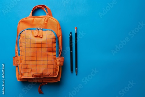 Orange backpack and blue stationary on blue background