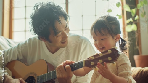Asian father teaching his daughter to play the guitar in their living room, creating a happy and joyful atmosphere in family.