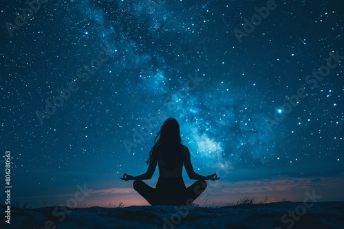 A woman is sitting in lotus position with her hands raised in the air in the middle of a field
