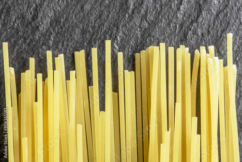 raw spaghetti pasta from durum wheat vertically on a dark background