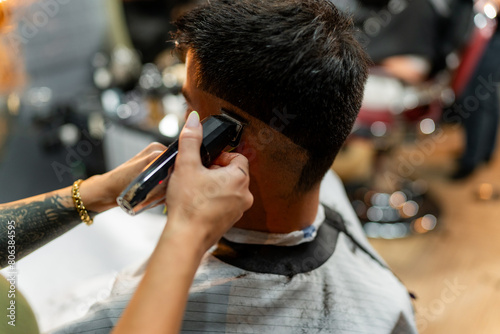 Close-up view of a female barber's hands expertly using clippers to perfect a male client's haircut, focusing on detail and craftsmanship in a stylish barber shop