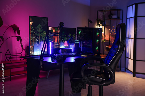 Playing video games. Stylish room interior with modern computer and gaming chair in neon lights
