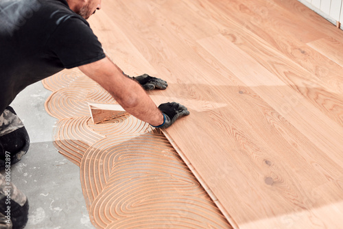 Professional handyman installing laminate flooring in a new apartment.