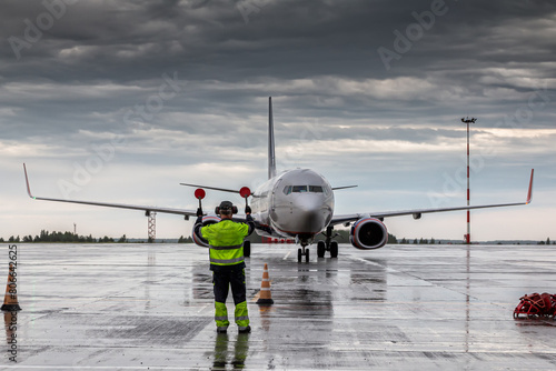 Aircraft marshalling at the aiport apron in rainy weather