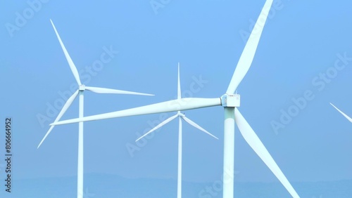 Aerial perspective reveals towering wind turbines against a serene sky, their rotating blades harnessing nature's power, a picturesque tableau of sustainable innovation. 