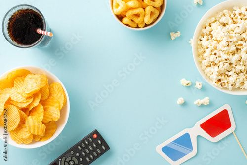 Dive into a home cinema adventure: top view of popcorn, crisps, soda, and streaming remote. Movie-themed decorations on pastel blue, ideal for text or advertising placement