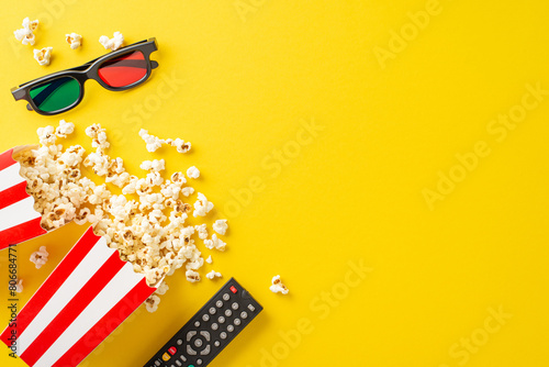 Stream exclusive movie night from home via TV app. Overhead shot of savory popcorn, 3D glasses, remote control. Yellow backdrop with space for text or ads