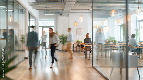 In the fast-paced environment of the modern office, people move swiftly in blurred motion, their actions contributing to the bustling energy of the bright business workplace.
