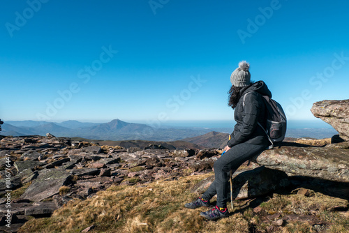 Mulher turista no alto da montanha sentada sobre uma rocha a apreciar a paisagem enquanto descansa