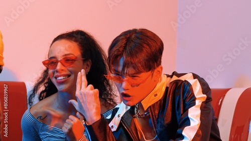 Close up of asian man and hispanic woman dancing together at party with led or neon light. Professional street dancer moving to freestyle and lively music while wear glasses and cloth. Regalement.