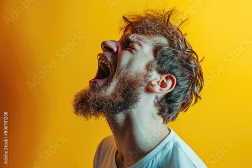 man screams. Portrait of young man shouting against yellow background