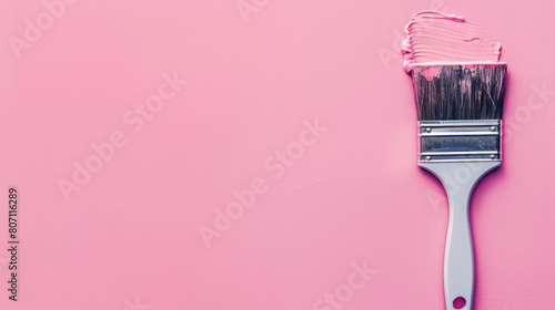 paintbrush with pink paint on bristles against a matching pink background, with copy space for text