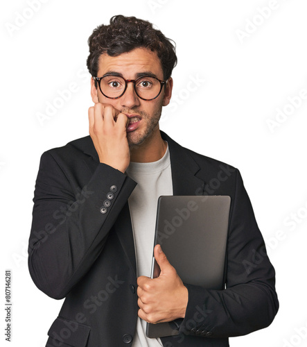 Young Hispanic businessman with laptop biting fingernails, nervous and very anxious.