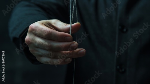 An illustration of manipulation. The hand holds strings to manipulate. The background is dark.