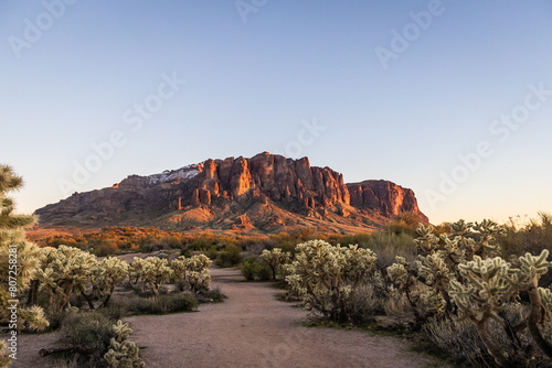 Evening photo of a hiking trail leading to Superstition Mountain in the distance outside of phoenix with a clear sky.