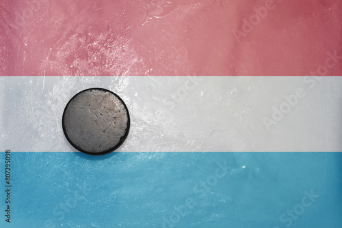 old hockey puck is on the ice with national flag of luxembourg .