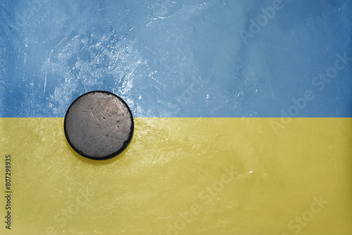old hockey puck is on the ice with national flag of ukraine .