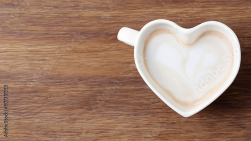 white mocka in a heart shaped cup on wooden background, wooden cafe layout