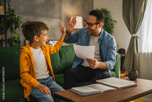 Happy and satisfied little boy show his father good grade on his test