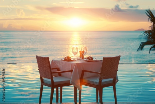Romantic dinner table near the beach beside the infinity pool at sunset