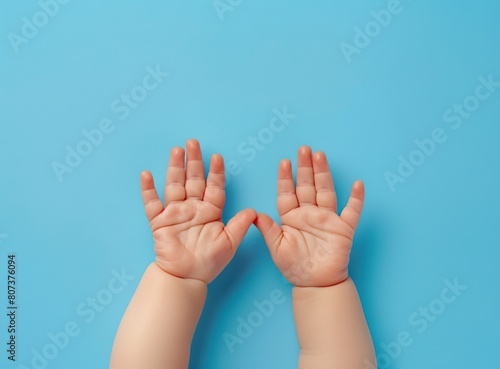 Beautiful little hands of a chubby baby on a blue background. Hands of a cute baby in top view on a light blue background.