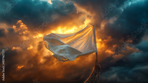 hand rise with white flag for surrender or peace sign against dramatic storm clouds in the sunset sky.