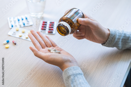 Sick ill asian young woman, girl hold tablet pill on hand pour capsule from medication bottle, painkiller medicine from stomach pain, head ache, pain for treatment, take drug or vitamin, health care.