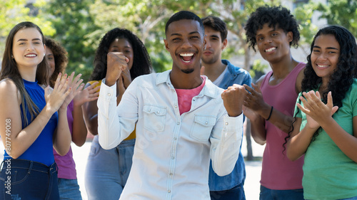 Successful cheering african american young adult with group of applauding people