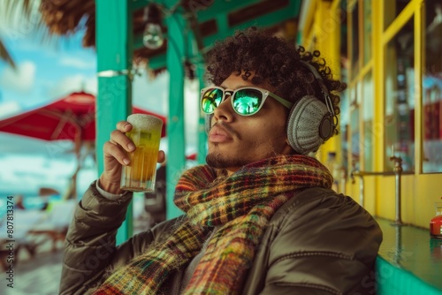 Young Latino man enjoying a cold beer at a vibrant beach bar