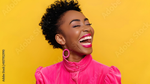 Happy optimistic African American woman in colorful pink clothes laughing isolated on yellow background