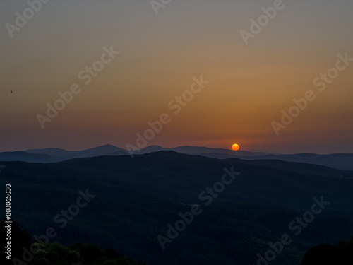 tarcza słońca dotykająca wierzchołków gór, koniec dnia w Toskanii