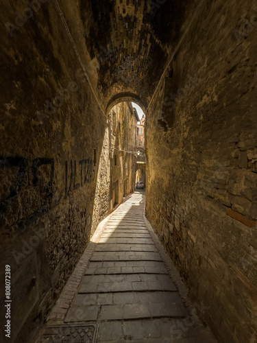 Wąska uliczka miedzy kamiennymi kamienicami na starym mieście w miasteczku Perugia, Toskania, Włochy