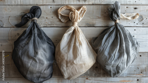 Three knotted fabric bags on wooden surface