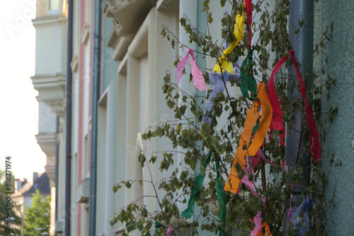 Small may tree with colorful crepe paper on a house wall in the Rhineland
