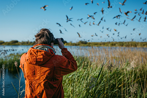 enthusiast birdwatching in marshlands with binoculars