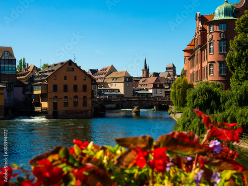 Peaceful cityscape of Strasbourg during summertime. Streets and canals of French city decorated with colorful flowers.