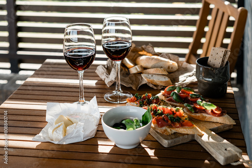 Glasses with red wine and tasty snacks on the table. Romantic dinner for a couples on summer terrace