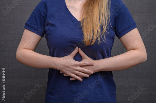 Młoda kobieta trzyma się za środek brzucha, ból i mdłości