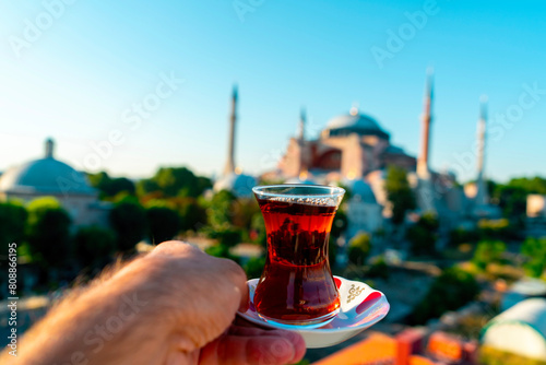 A man drinks Turkish tea opposite the Hagia Sophia Mosque. The man drinks his tea while admiring the view. Istanbul Turkey.