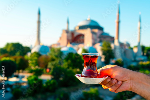 The Hagia Sophia Mosque. Man drinks black Turkish tea in front of the view. In the photo, the tea is clearly captured, while Hagia Sophia is blurred. Istanbul Turkey..