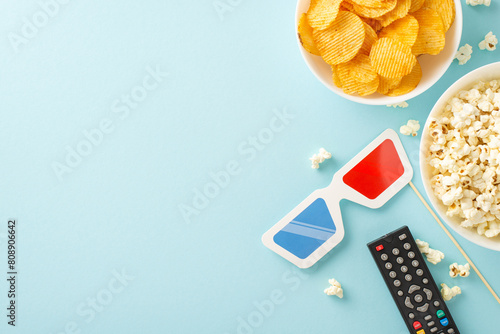 Create your own cinema magic: top view of popcorn, snacks, 3D glasses decor on stick, remote control. Movie-themed decoration on pastel blue background, setting scene for memorable movie night at home