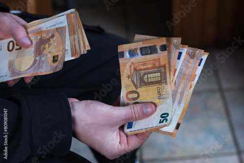 gros plan sur des mains qui tiennent une liasse de billets de 50 euros pour effectuer un paiement