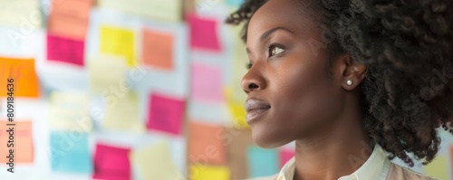 African American woman with colorful sticky notes on wall. Modern workplace concept.