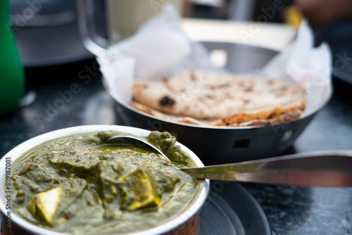 A bowl of Palak Paneer made of Paneer cheese dipped in mildly spiced Spinach gravy on wooden background.