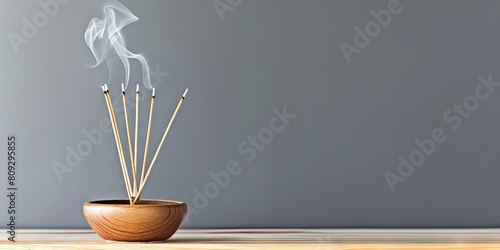photo of incense sticks smoking in incense holder on table on solid background with copy space