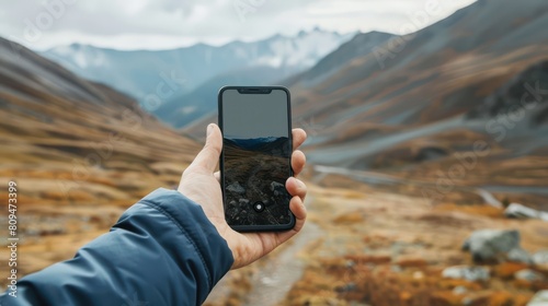 A person in a remote area holding up a smartphone with no signal bars, indicating the inability to connect to the internet.